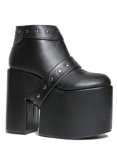 Load image into Gallery viewer, side view of black vegan leather super tall 6" heel, 4" platform sleep design boot. Boot has a rivet studded strap that wraps around and is removable or attachable with Velcro. Boot has black EVA platform.
