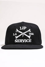 Load image into Gallery viewer, front view of Black hat with white embroidery that reads "LIP SERVICE LA USA" on the front with crossbones. Snaps on the back.