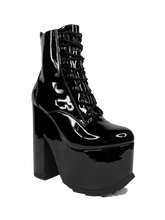 Load image into Gallery viewer, outer view of Black vegan shiny patent leather tall military style platform boot with black cotton laces and black inner zipper. Front of platform has a fanned grip for better stability when walking.