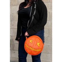 Load image into Gallery viewer, woman wearing bag on shoulder. bag is orange with yellow eyes and yellow teeth, with a black adjustable strap. based on sam's jack o lantern in the movie trick r' treat