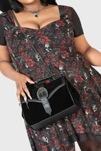 Load image into Gallery viewer, Person holding a black handbag with a floral dress
