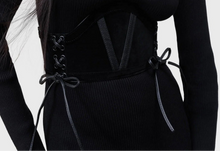 Load image into Gallery viewer, Model wearing a black dress with fashion belt layered over top on a white background
