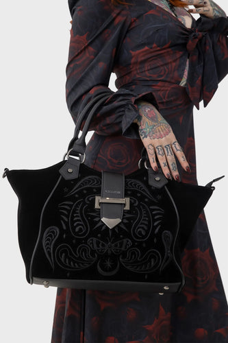 model holding a black embroidered handbag with intricate designs