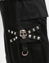 Load image into Gallery viewer, Waist-down view of baggy black punk-style cargo pants featuring silver pyramid studs, hanging side straps, a drawstring waist, and chunky black boots against a white background.
