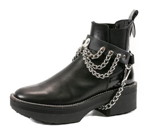 black ankle boot displaying black leather boot strap with front hanging three row silver chains and hanging silver chain underneath booth