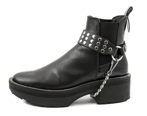 black ankle boot displaying black boot strap with three rows of multiple silver riveted studs and hanging silver chain underneath