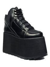 Load image into Gallery viewer, outer view of black vegan leather platform shoe with EVA platform. Shoe looks like a sneaker, but super tall! Shoe has nylon details and mesh lining. Bottom of platform has a &quot;fanned&quot; grip to make the platform more stable.
