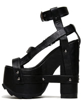 Load image into Gallery viewer, outer view of black vegan leather strappy platform sandal with 6.5&quot; heel. Sandal has gunmetal hardware, adjustable ankle strap and adjustable side strap. Bottom of front platform has a fanned grip for better stability.
